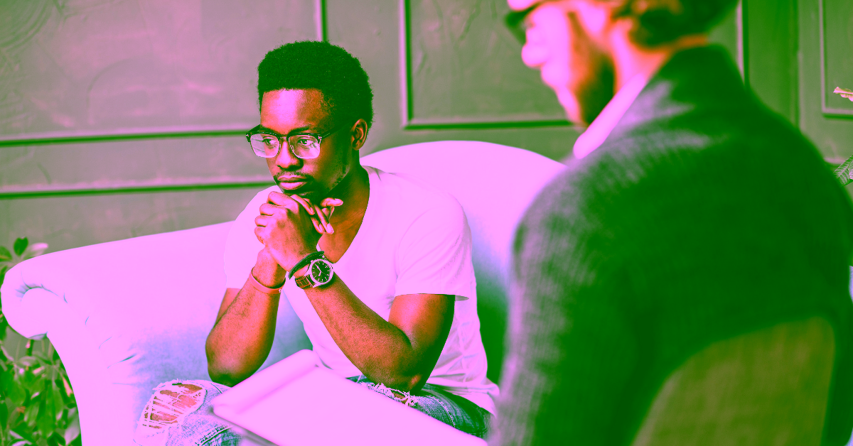 An African-American man in a therapist office, sitting on the couch discussing if mental health conditions are genetic or enivonrmental