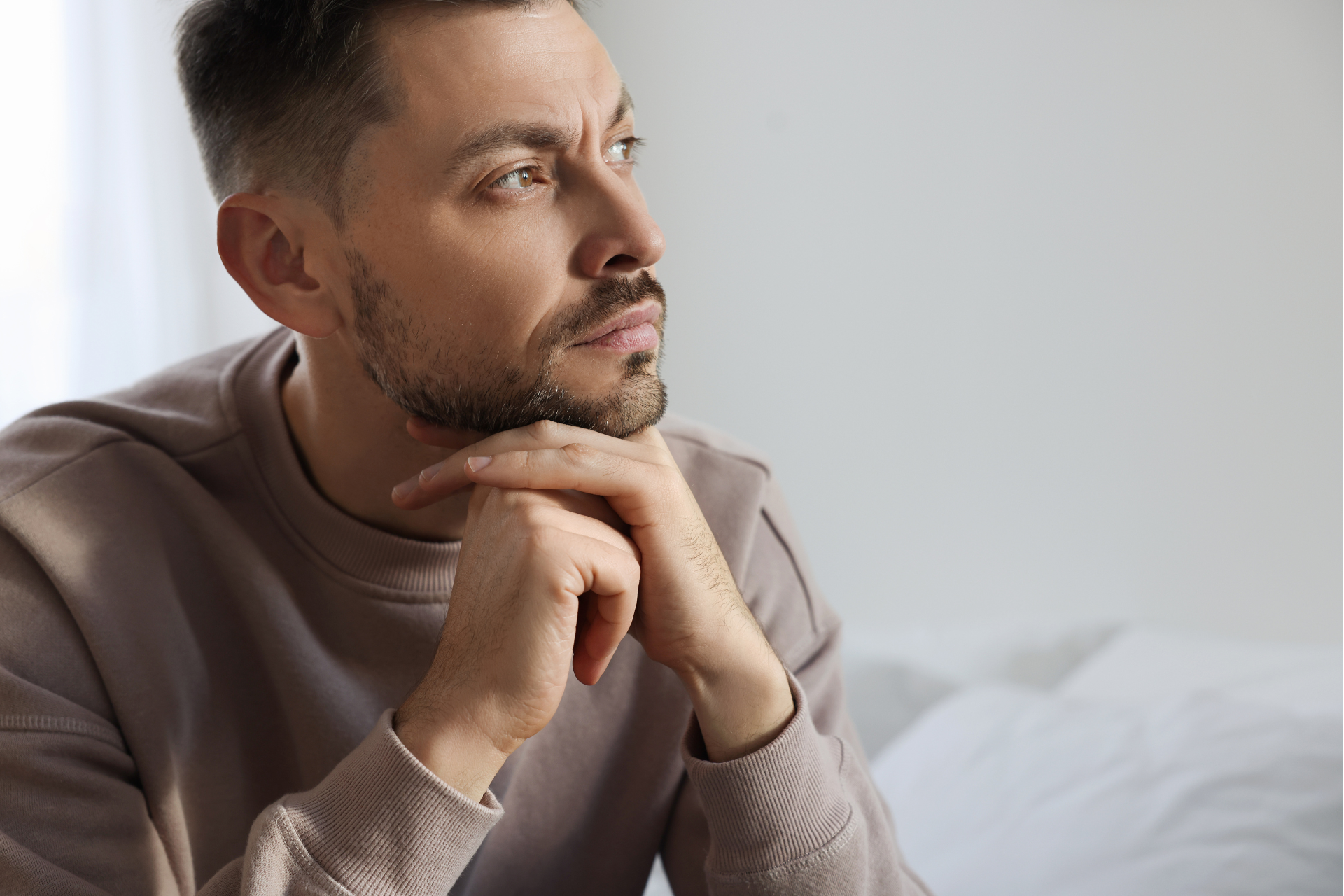 A man with his chin resting on his hands. He struggles with bipolar disorder.