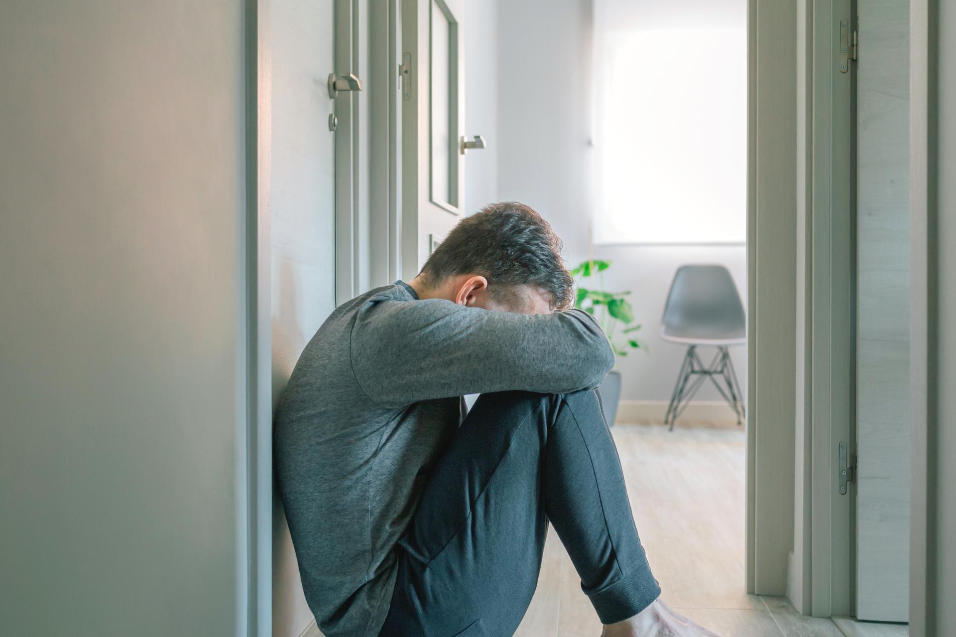 A man sitting on the floor hiding his face struggling with crack addiction