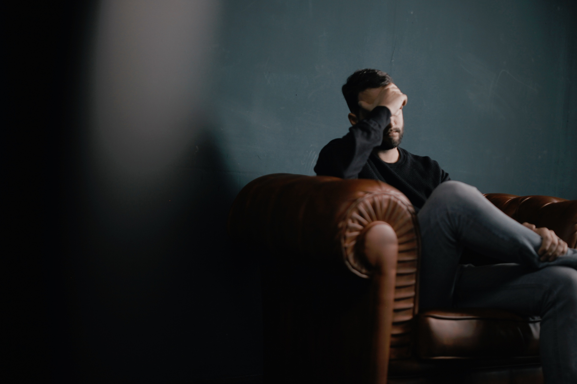 A man sitting on a couch in therapy with his head in his hands suffering from methamphetamine addiction