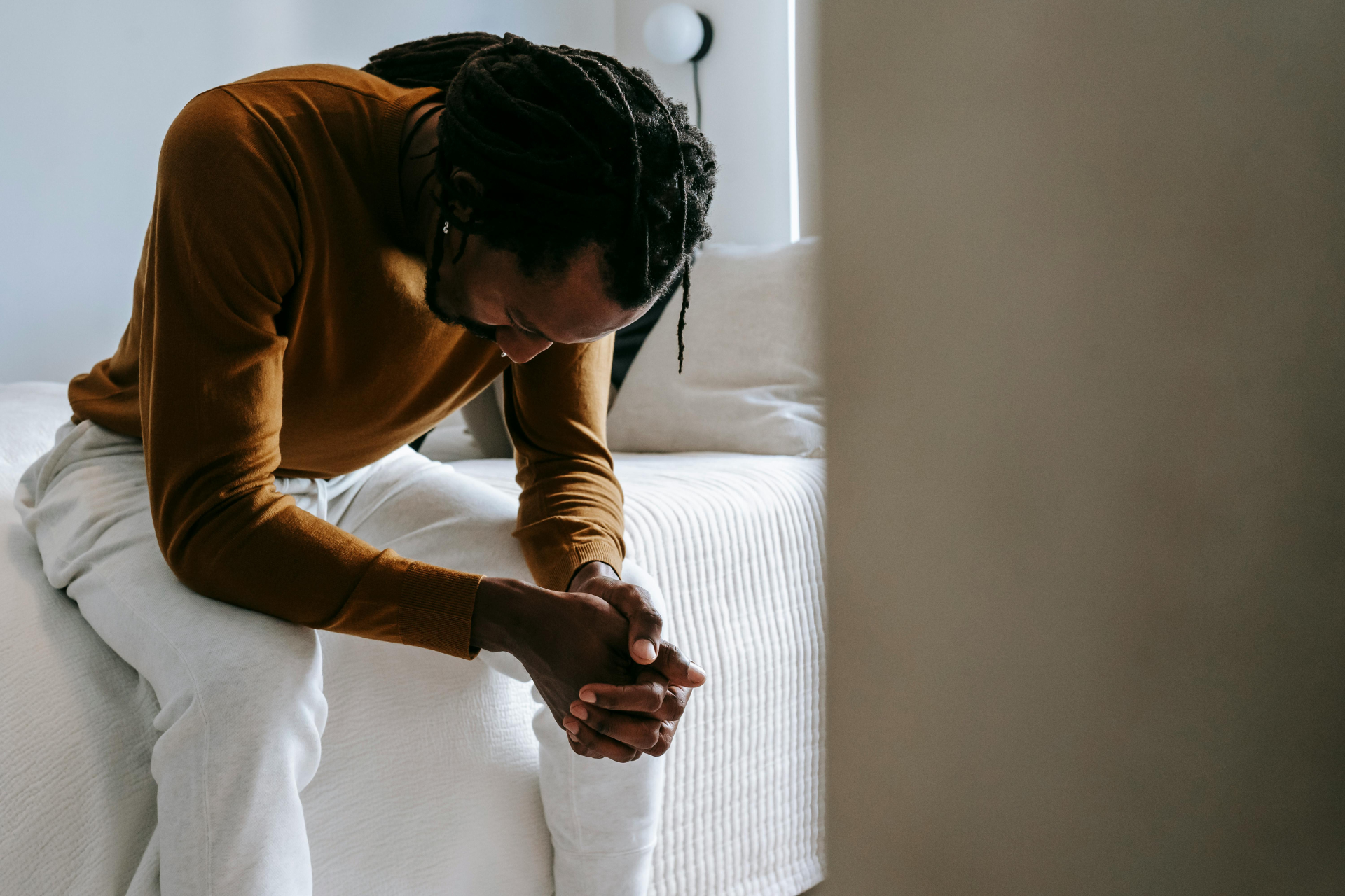 Man resting on the side of his bed, struggling with stimulant addiction.