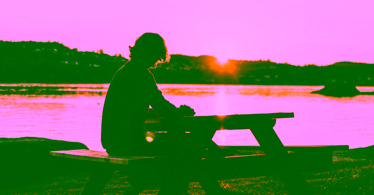 A man sitting on a picnic table bench, overlooking water while in IOP at Milton