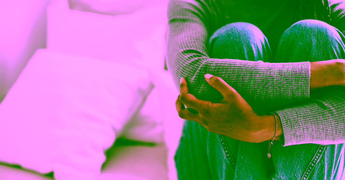 A woman sitting with her arms wrapped around her legs.