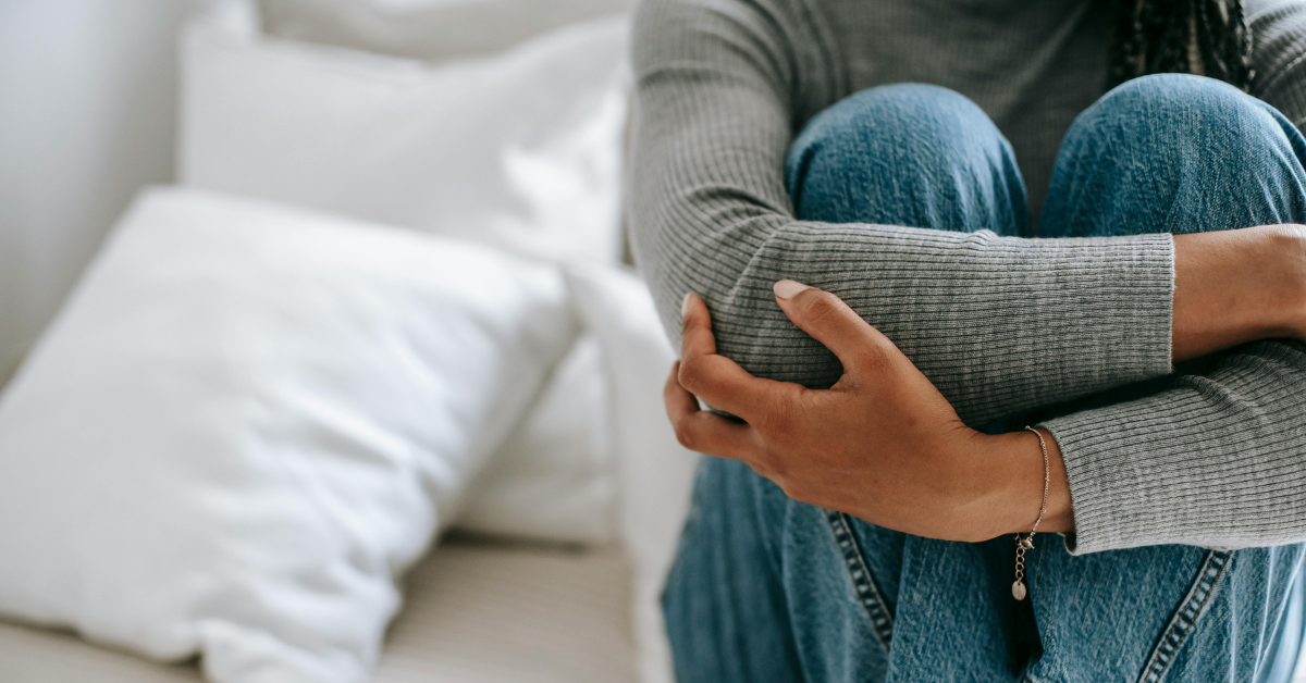A woman sitting with her arms wrapped around her legs.