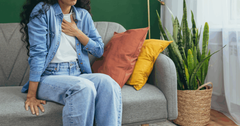 A woman on a couch with her hand on her chest having a panic attack