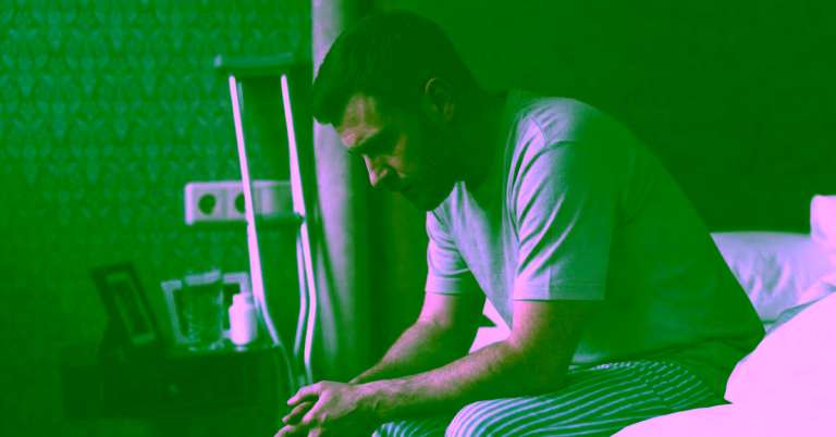 man with opiate addiction sitting on side of bed with contemplative emotions